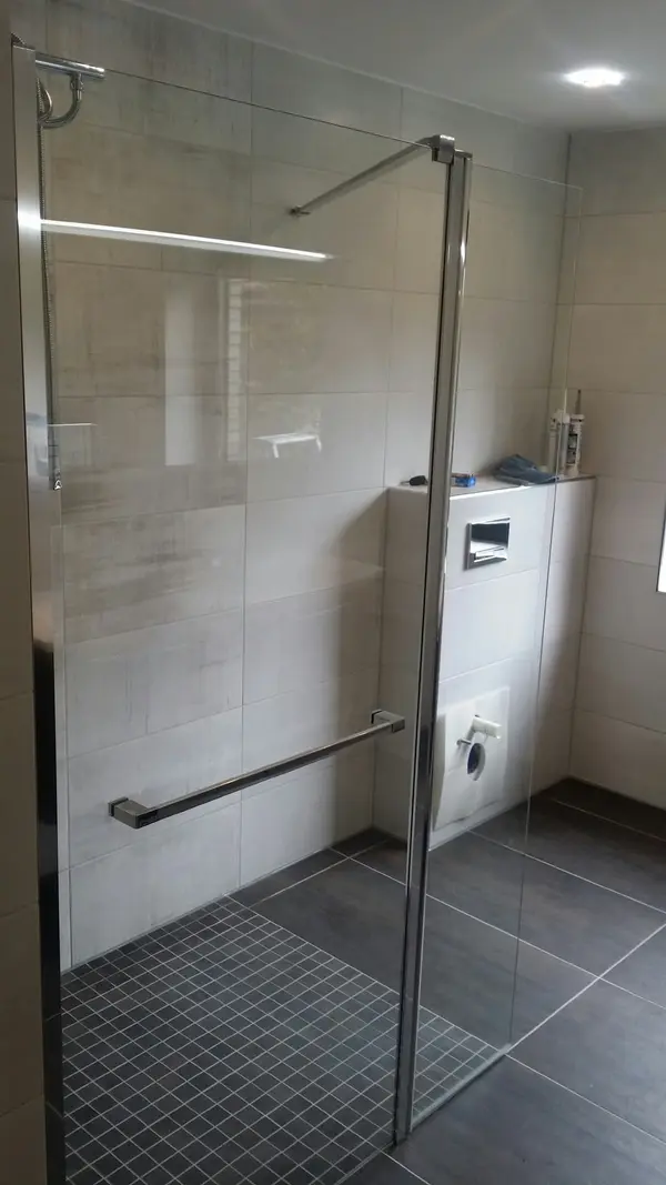 Kabina prysznicowa walk-in ze szklaną ścianką, jasne płytki na ścianach i&nbsp;mozaika na podłodze