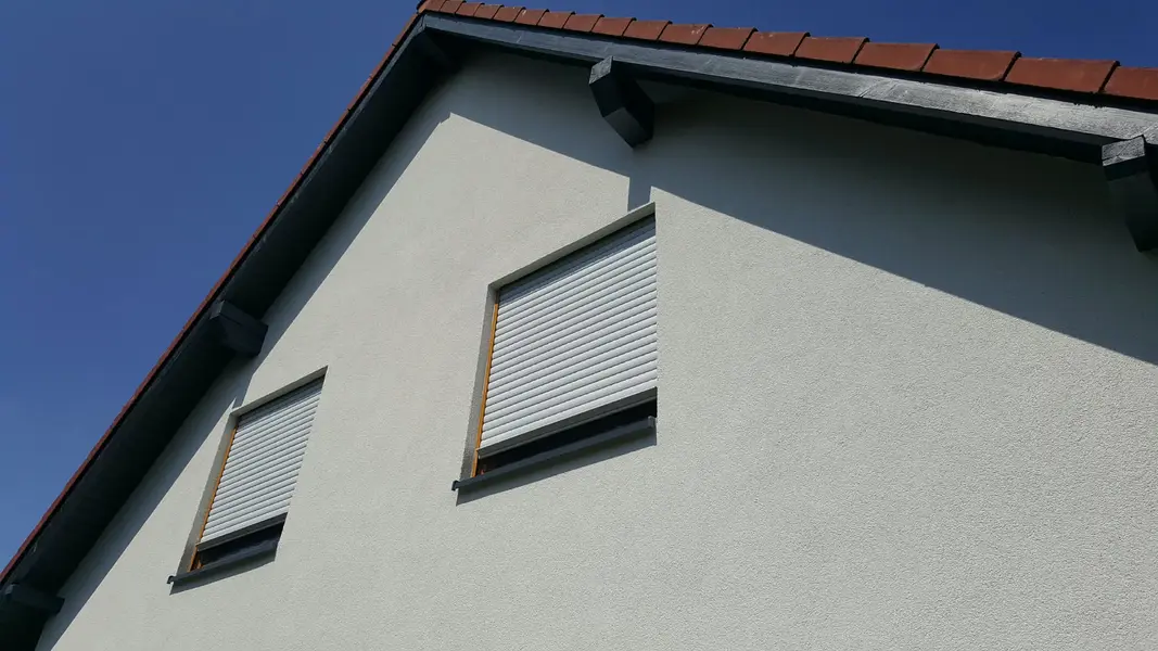 Dwa okna z&nbsp;roletami zewnętrznymi w&nbsp;szczycie domu